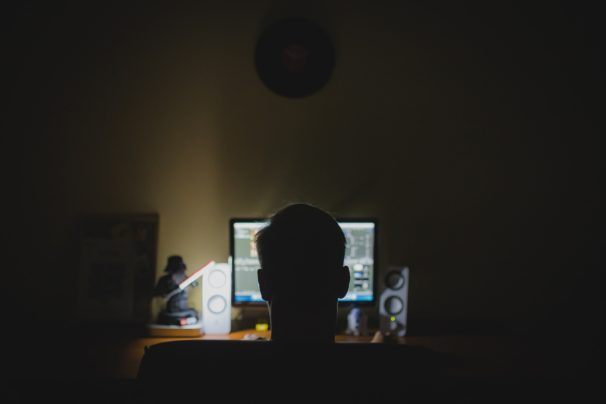 man in the dark infront of a computer screen