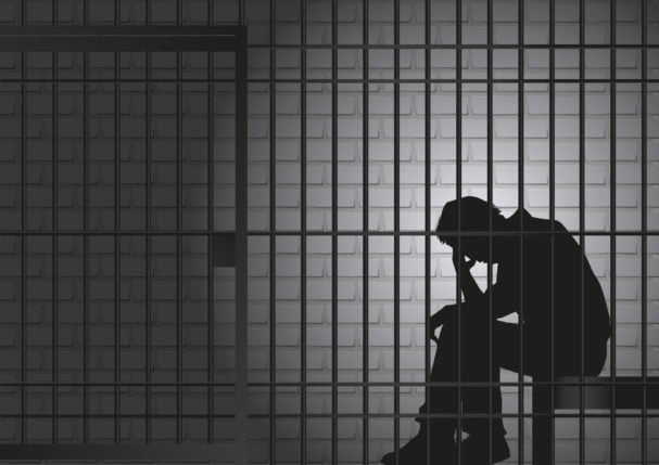 silhouette of a man behind jail cell bars