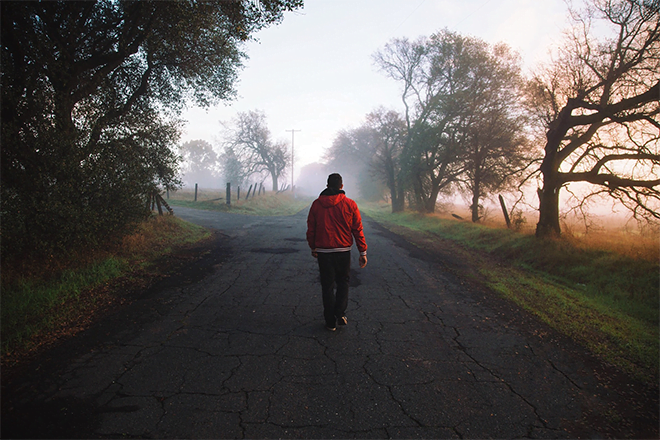 man walking in the middle of a foggy road