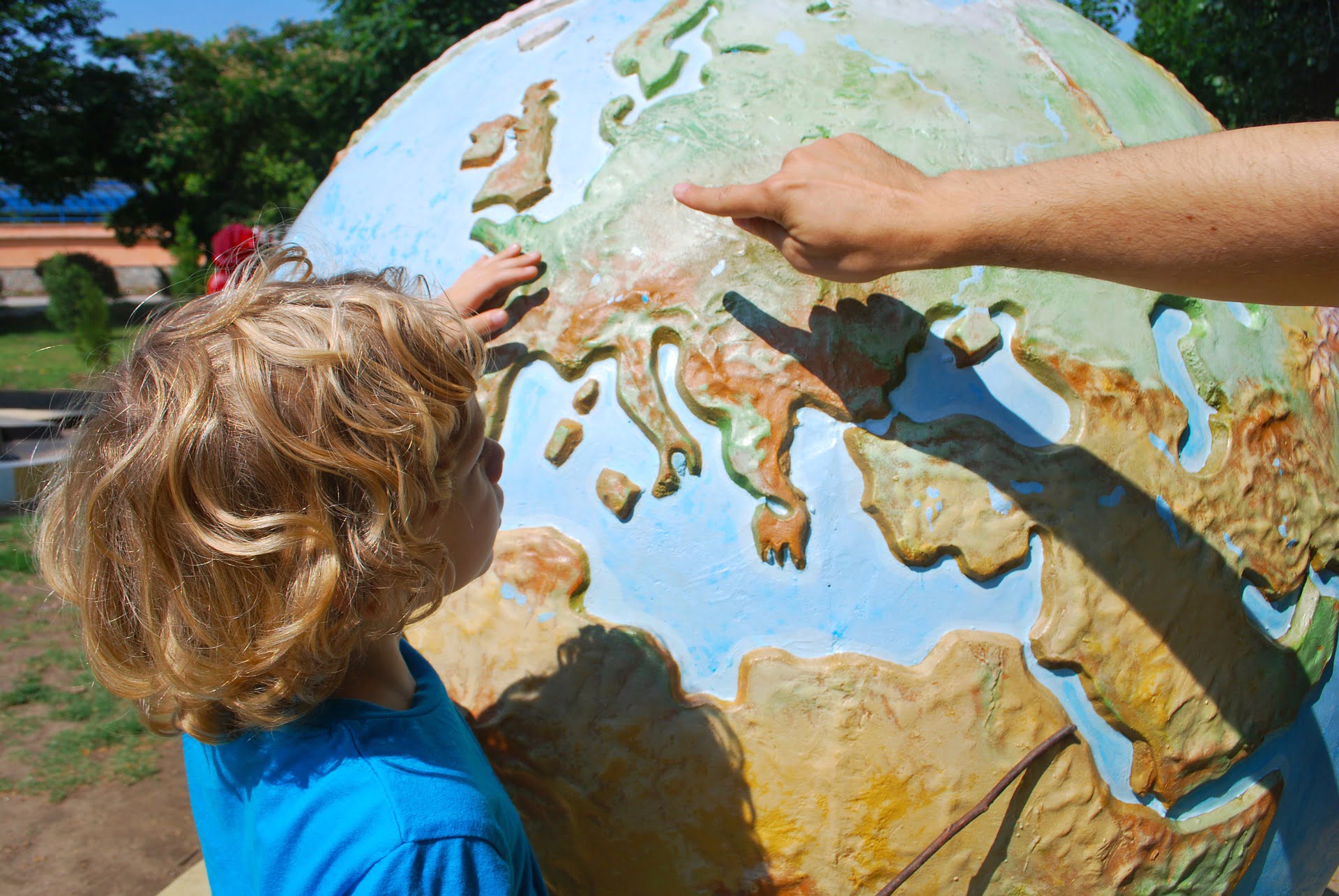 child infront of big globe pointing