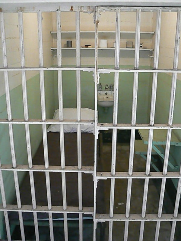 closed jail cell, bed, sink, table
